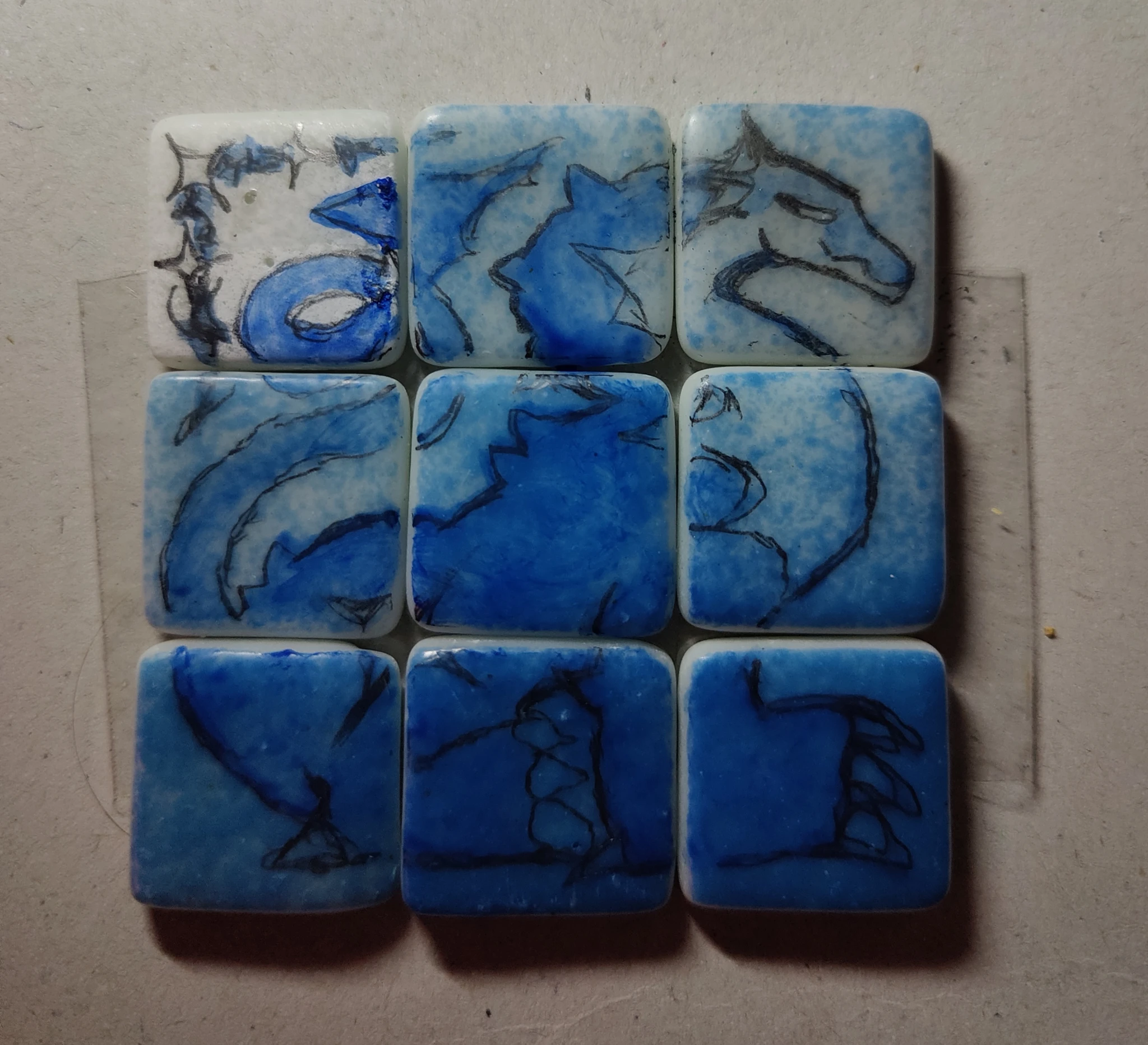 Blue big dragon painting on nine small pool tiles. It has a curly and pointy tail plus big claws.